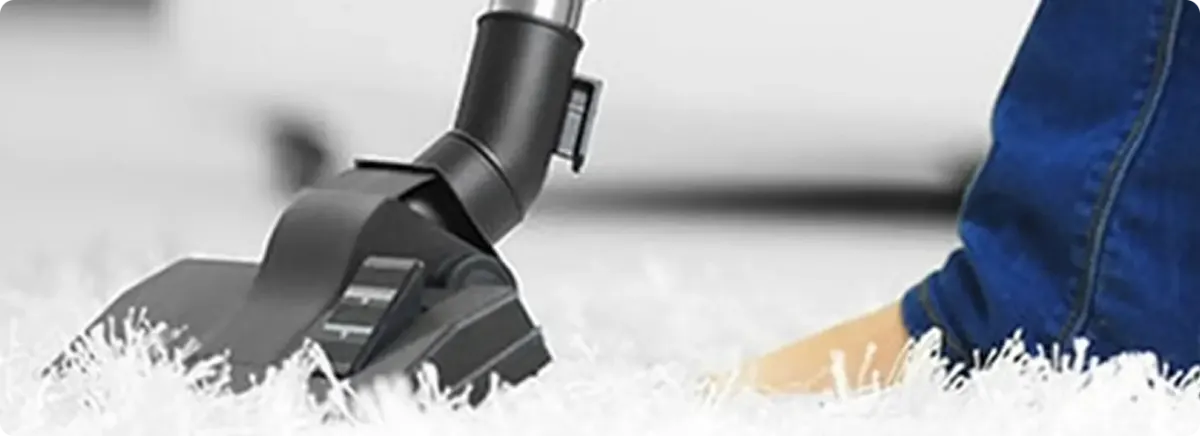 Close-up of a professional vacuuming a white carpet in Garland.